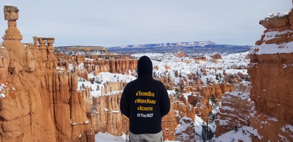 A person wearing aCooke Scholar hoodie overlooks a canyon.
