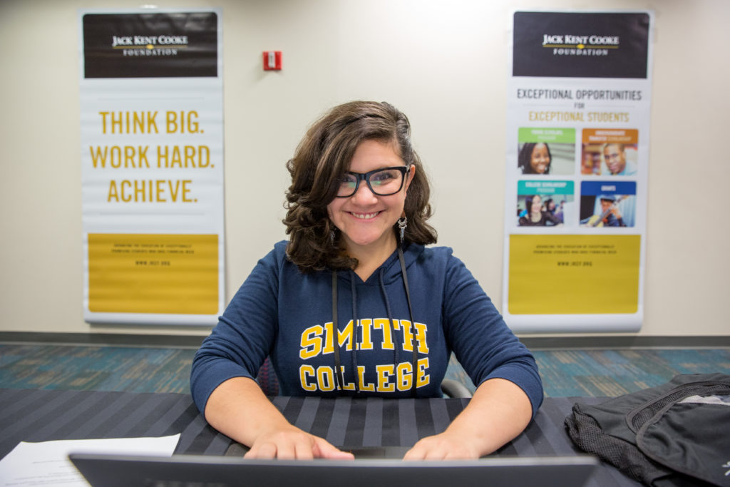A student in a Smith College sweatshirt types on a laptop.